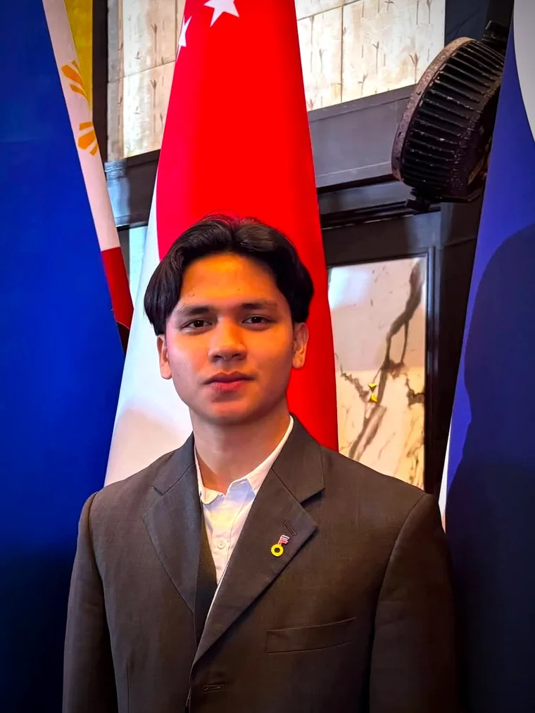Lawrence Panes in a tailored suit and lanyard, duotoned into the indigo-and-gold of the star chart like a navigator at rest.